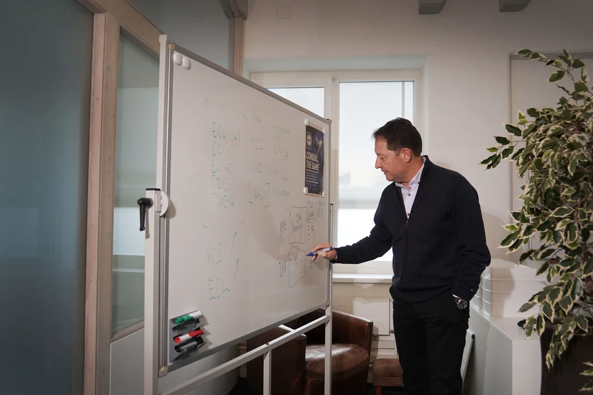 Roger Feiner erklärt an einer Tafel in seinem Büro, wie die Spielformate im Cricket funktionieren.